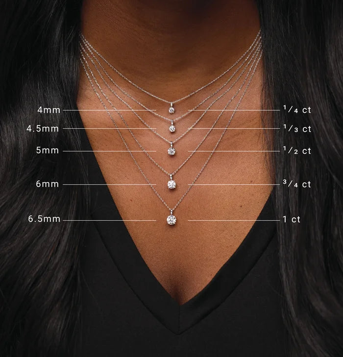 Necklace with diamond pendants of different sizes on a person wearing a black top.