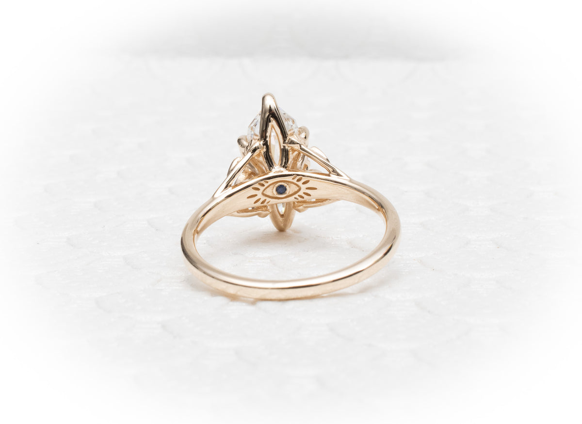 Custom 14K yellow Gold tree of life inspired engagement ring with an evil eye sapphire and Marquise Diamond Centre Stone